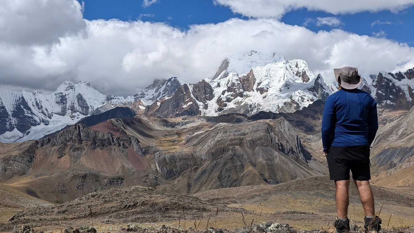 Bărbat stând în fața unui munte din lanțul muntos Cordillera Huayhuash din Peru și bucurându-se de o priveliște pitorească
