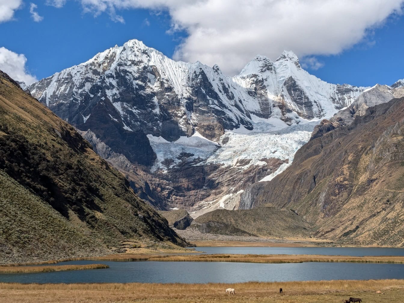 Lago em um vale com montanhas cobertas de neve na Cordilheira Huayhuash, uma cordilheira nos Andes no Peru