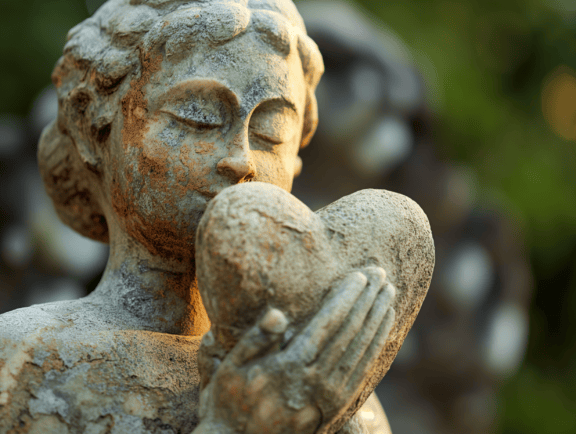 Statuie de piatră a unei fete care ține o inimă în mâini