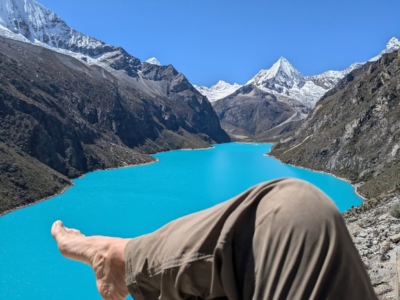 Person’s barefoot leg in foreground with Paron lake in the background at the Cordillera Blanca in the Andes of Peru