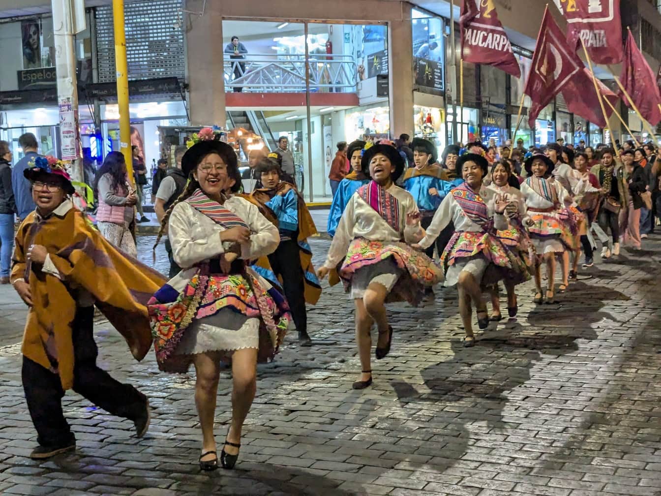 Orang-orang dengan pakaian rakyat tradisional Peru menari di jalan selama festival jalanan