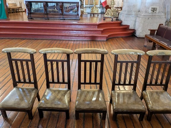 Reihe alter Holzstühle in einer katholischen Kirche in Peru