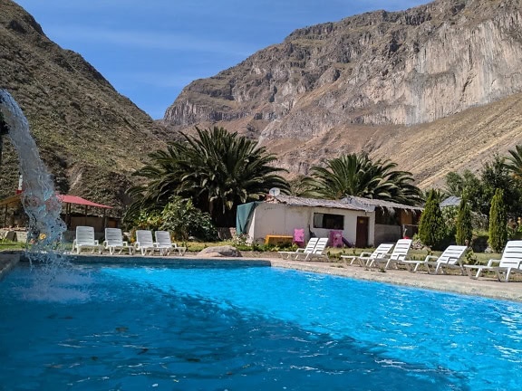 En resort på landsbygden i Peru med en pool med vita solstolar och en liten bondgård
