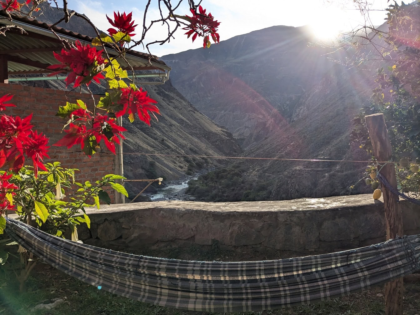 Hamac-lit dans le jardin face à une vallée avec des rayons de soleil brillants derrière la montagne
