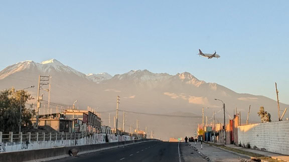 A passenger plane flying over a street road in Peru