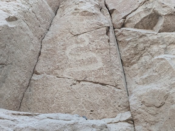 En hällristning huggen i sten föreställande ett djur som liknar en orm eller drake, en stenålderskonst som finns i Peru i Sydamerika