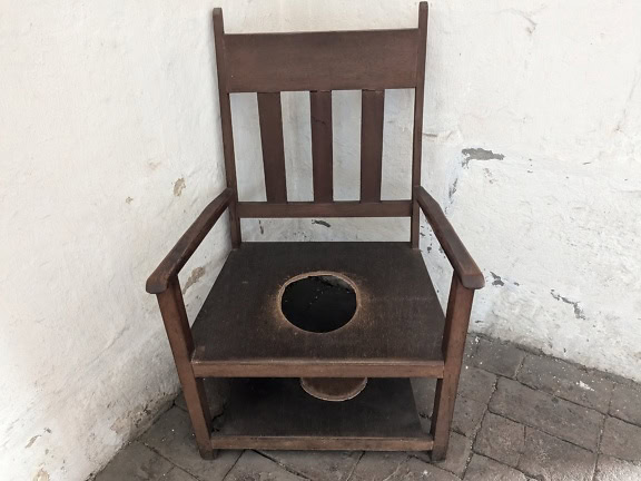 Stará drevená stolička s otvorom v strede používaná ako toaleta n kláštor Santa Catalina v Arequipe v Peru