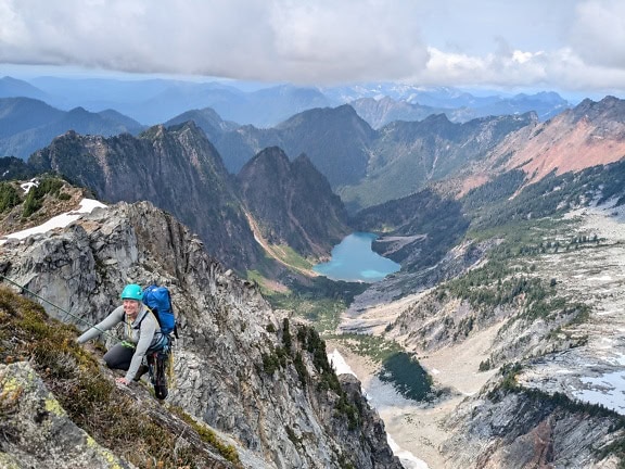 Žena horolezkyně na vrcholu pohoří s panoramatem vrcholu Vesper v Severních Kaskádách ve Washingtonu v pozadí