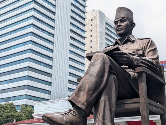 Statue of a man sitting on a chair at Soekarno monument in Jakarta, Indonesia