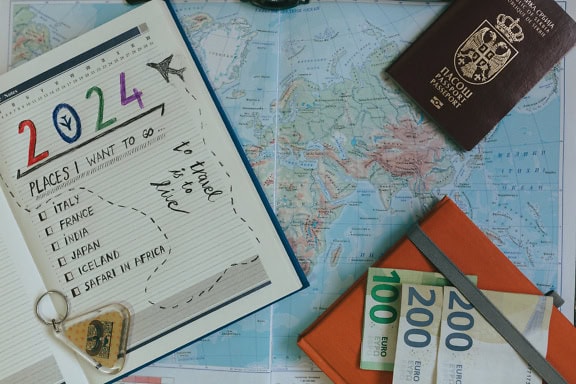 A geographic map with a passport, money and a planning notebook with a travel plan and a countries to visit