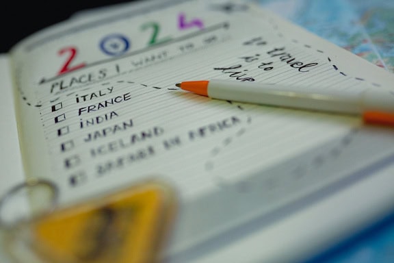 A pencil on a travel planning notebook with a itinerary and countries to visit in 2024 with a France in the focus