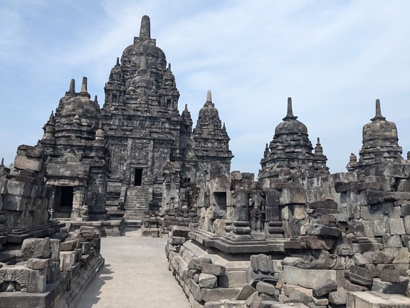 Un sitio arqueológico y de la UNESCO con un edificio de piedra con una pasarela de piedra en el templo Candi Prambana, Bahasa Indonesia