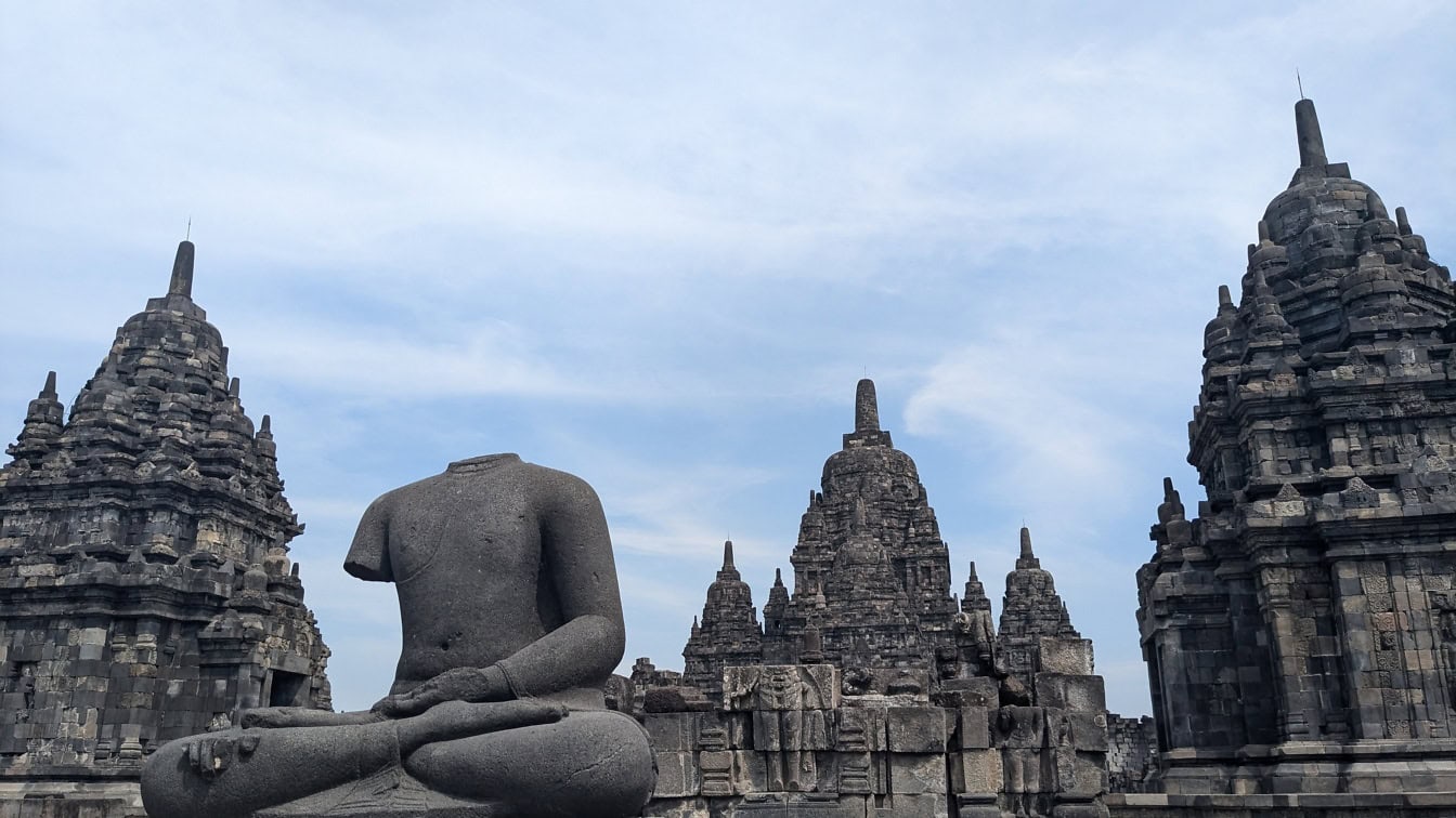 Socha muže sedícího v meditační póze před chrámem Prambanan v Indonésii, který je zapsán na seznamu světového dědictví UNESCO