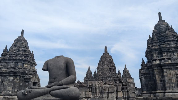 Statue av en mann som sitter i meditasjonsstilling foran Prambanan-tempelet i Indonesia, et UNESCOs verdensarvsted