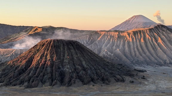 Pasmo gór Bromo z dymem wydobywającym się ze szczytu krateru wulkanicznego, wulkaniczny krajobraz na Jawie, Indonezja