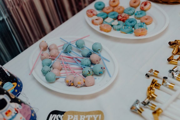 Plates of donuts and lollipop on a table at birthday party