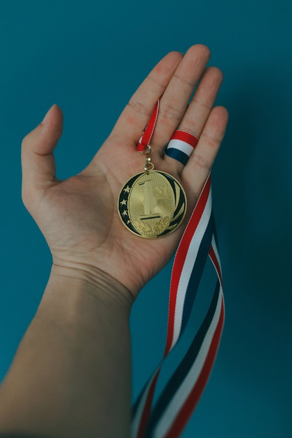 Un primer plano de una medalla de oro en la mano, un premio por ganar el 1er lugar en la competencia