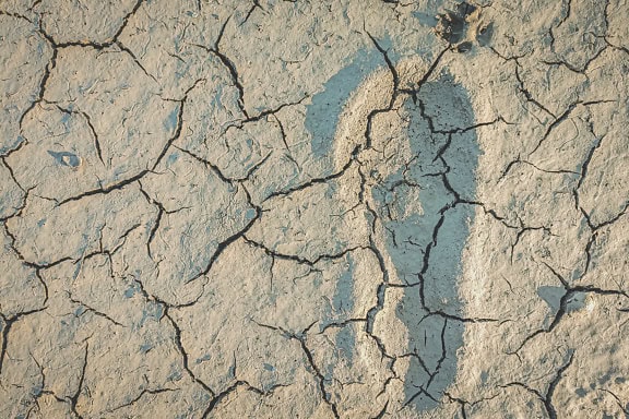 Uma impressão do pé de uma pessoa na lama rachada, um close-up de uma pegada em um solo seco durante a seca