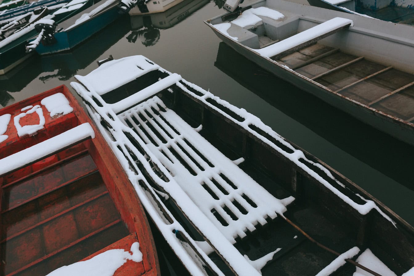 Närbild av snötäckta små fiskebåtar i marinan