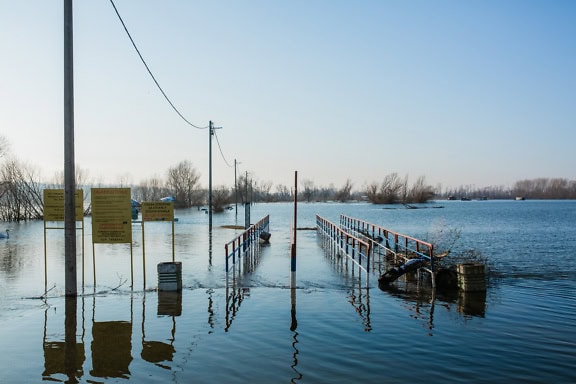 Overstroomde voetgangersbrug met waarschuwingsborden bij het Tikvara-meer, Bačka Palanka, Servië