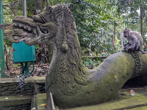 Statue of a dragon with a monkey sitting on it at Ubud Sacred Monkey Forest in Bali, Indonesia