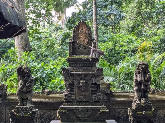 Singe debout sur une structure en pierre dans un temple hindou au sanctuaire de la forêt sacrée des singes d’Ubud, Bali, Indonésie