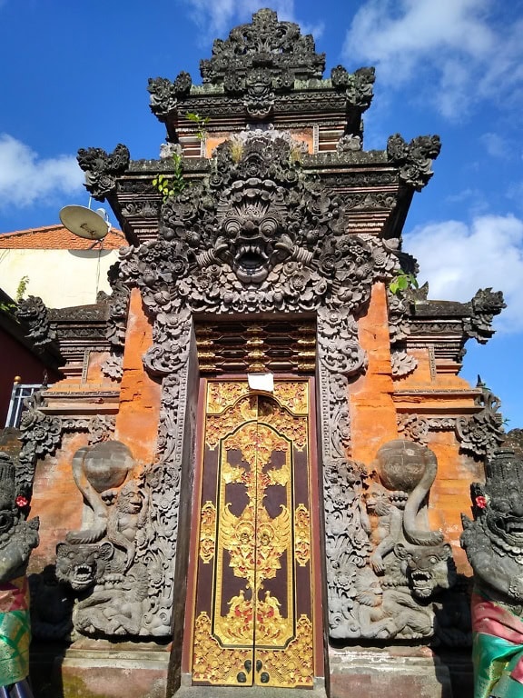 Ușa din față ornamentată a palatului regal cu statui la templul Goagajah, un sanctuar hinduist antic din Ubud, Bali, Indonezia