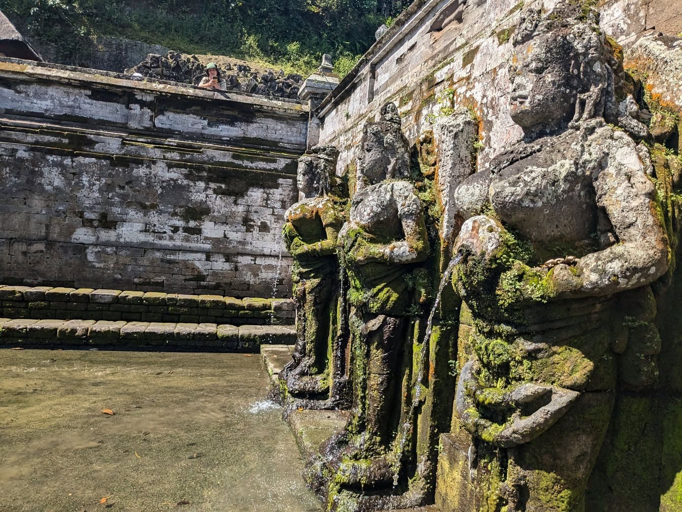 Ein balinesischer Brunnen mit Steinstatuen von Frauen im Goa Gajah Hindu-Tempel in Ubud, Bali, Indonesien