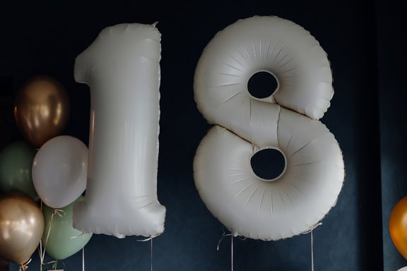 Ballons blanc-gris en forme de chiffre dix-huit (18), décoration lors d’une fête d’anniversaire pour célébrer l’âge adulte