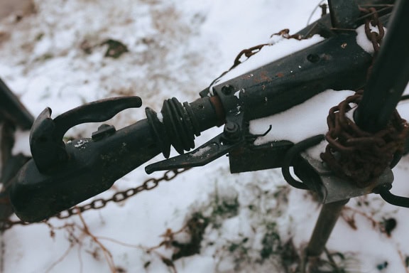 An iron trailer hook of a car’s trailer with a with a rusty chain