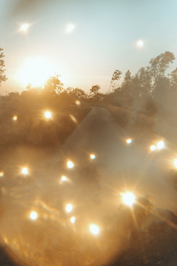 Photograph of a countryside road with artistic blur and intentional shining reflections of light depicting artistic freedom inspired by sunlight