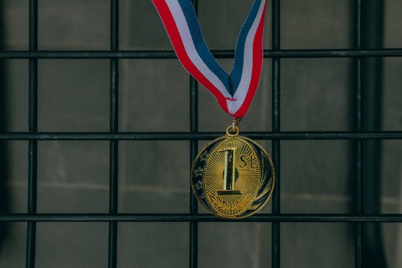 Uma medalha de ouro por ganhar o 1º lugar pendurado em uma fita vermelha, branca e azul, um sonho de ganhar o campeonato olímpico