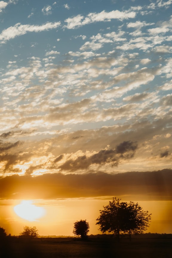 Zonsopgang over platteland met hemel veranderende kleuren van helder blauw naar oranje-geel