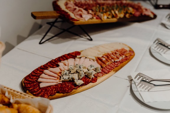 Wooden trays of spicy pork sausage, purloin, meat and cheese with fungus on a table, a perfect appetizer