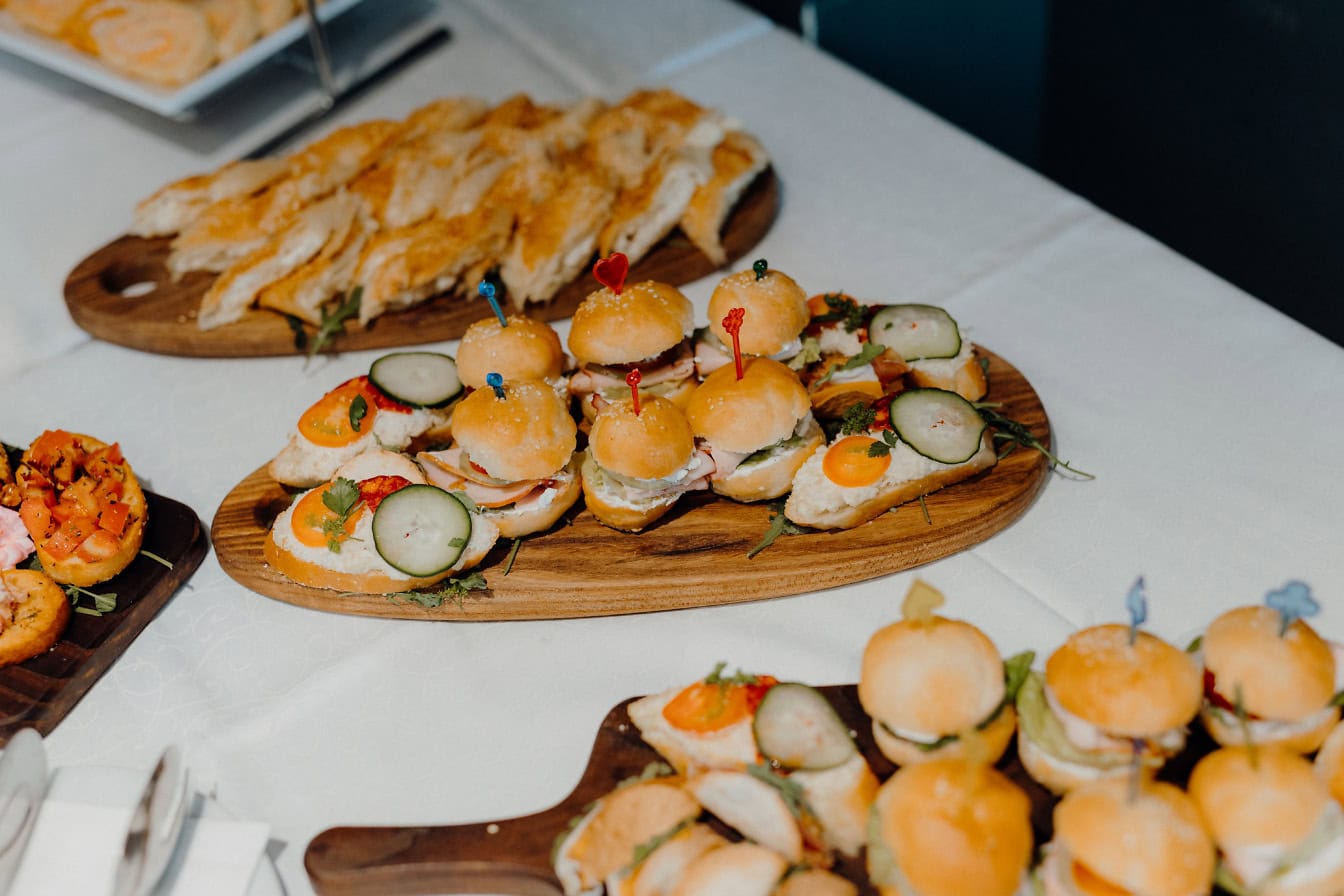 A table with plates of miniature burgers and sandwiches, fast food for a snack on the go