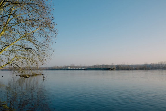 Großes Lastschiff auf einer Donau an einem ruhigen Tag mit strahlend blauem Himmel