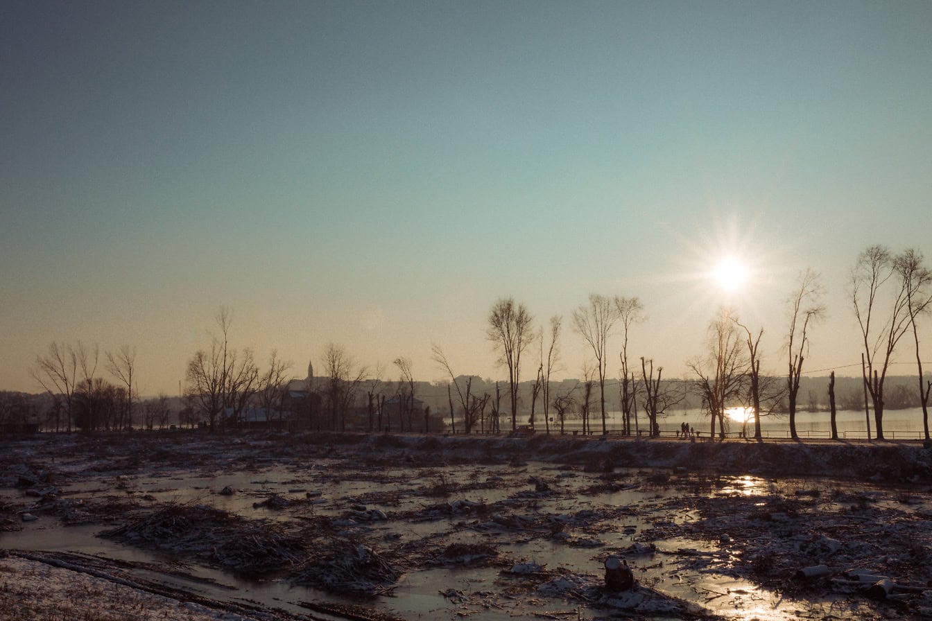 Panorama poplavljenog blatnjavog polja s jedne strane ceste i s jezerom s druge strane u sumrak