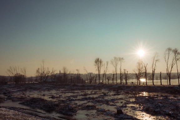 Panorama eines überfluteten Schlammfeldes auf der einen Seite der Straße und mit einem See auf der anderen Seite in der Abenddämmerung