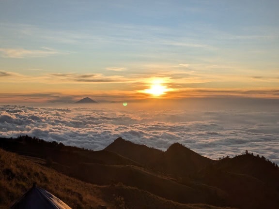 Zachód słońca nad chmurami i górą Rinjani, aktywnym wulkanem w Indonezji na wyspie Lombok