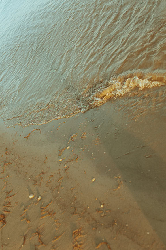 Golven die op het zandige rivierstrand beuken