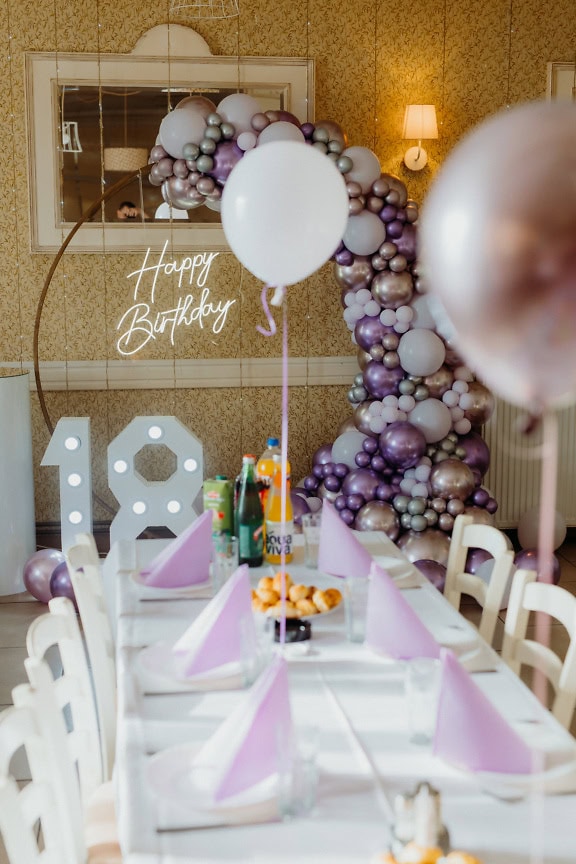 Enseigne au néon blanc Joyeux anniversaire avec ensemble de table et décorations de ballons lors d’une fête d’anniversaire pour célébrer l’âge adulte