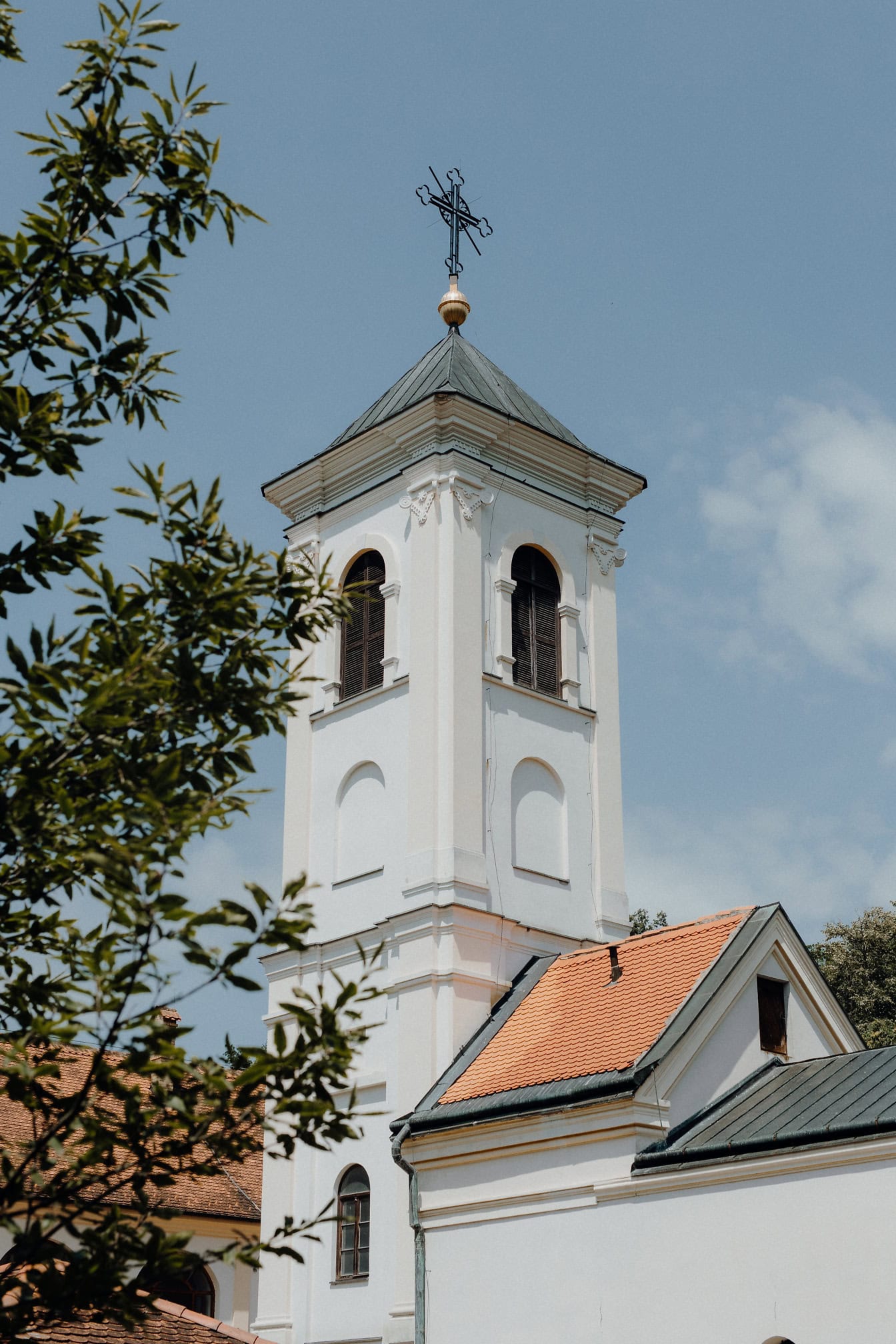 Bílá zvonice s křížem na vrcholu kláštera Djipsa nebo Divsa, kláštera srbské pravoslavné církve ve Fruské Goře