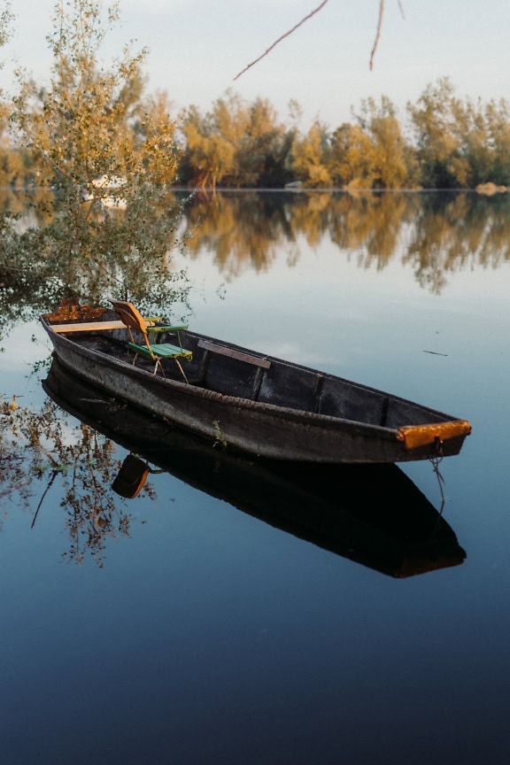 Hölzernes Fischerboot mit Stuhl darin auf dem See