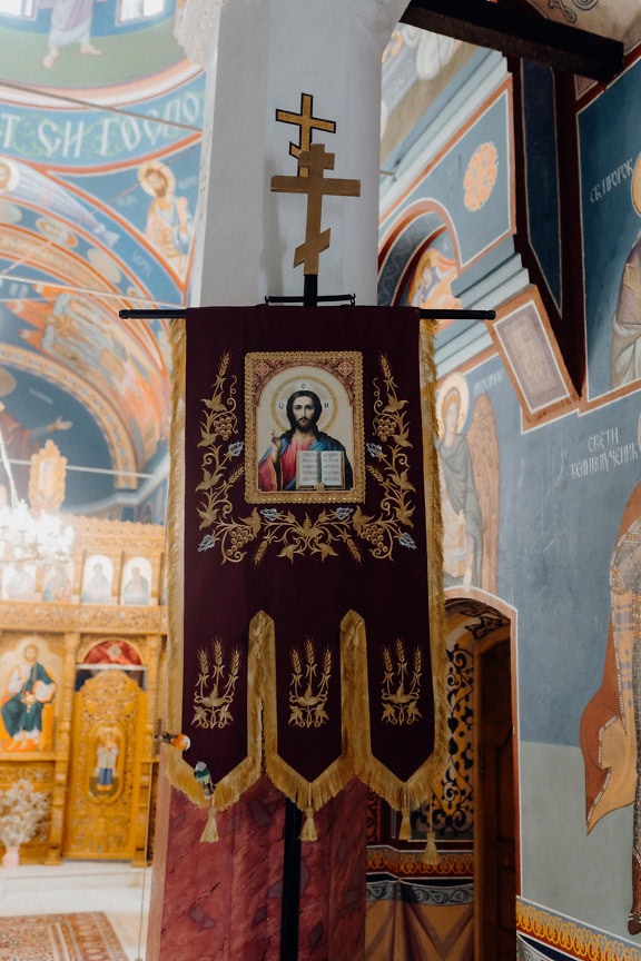 Estandarte religioso con una imagen de Jesucristo de Nazaret que cuelga de un pilar con una cruz en una iglesia ortodoxa