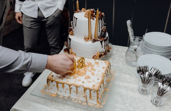 Un camarero encendiendo una vela en forma de número 18 en un pastel de cumpleaños, una ilustración de la fiesta de celebración del decimoctavo cumpleaños o la edad adulta