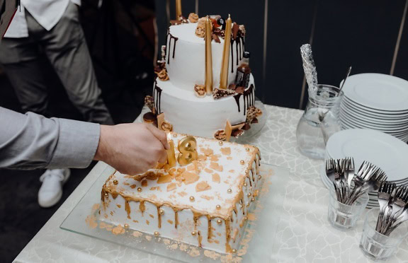 Person lighting up a candle in a shape of number 18 illustrating celebration of eighteenth birthday or adulthood