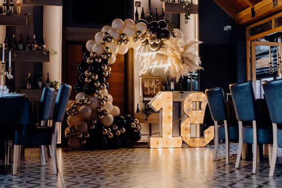 Ballonboog met Happy Birthday neonbord in een gezellige sfeer van wijnrestaurant, een decor om achttien (18) verjaardag of een volwassenheid te vieren