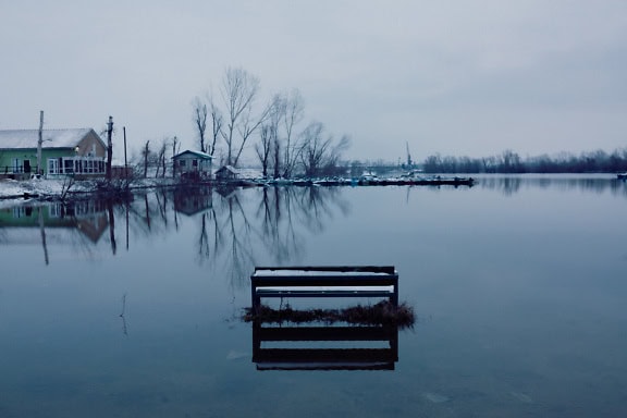 Overstroomd gebied van meer met besneeuwde bank in een koud winterwater