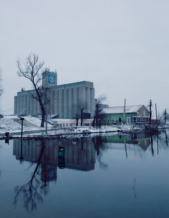 A silo building on a coast of lake at winter time