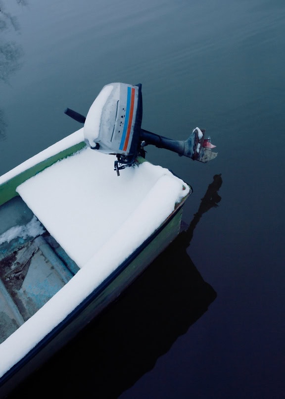 Motor di perahu motor nelayan kecil dengan salju di atasnya